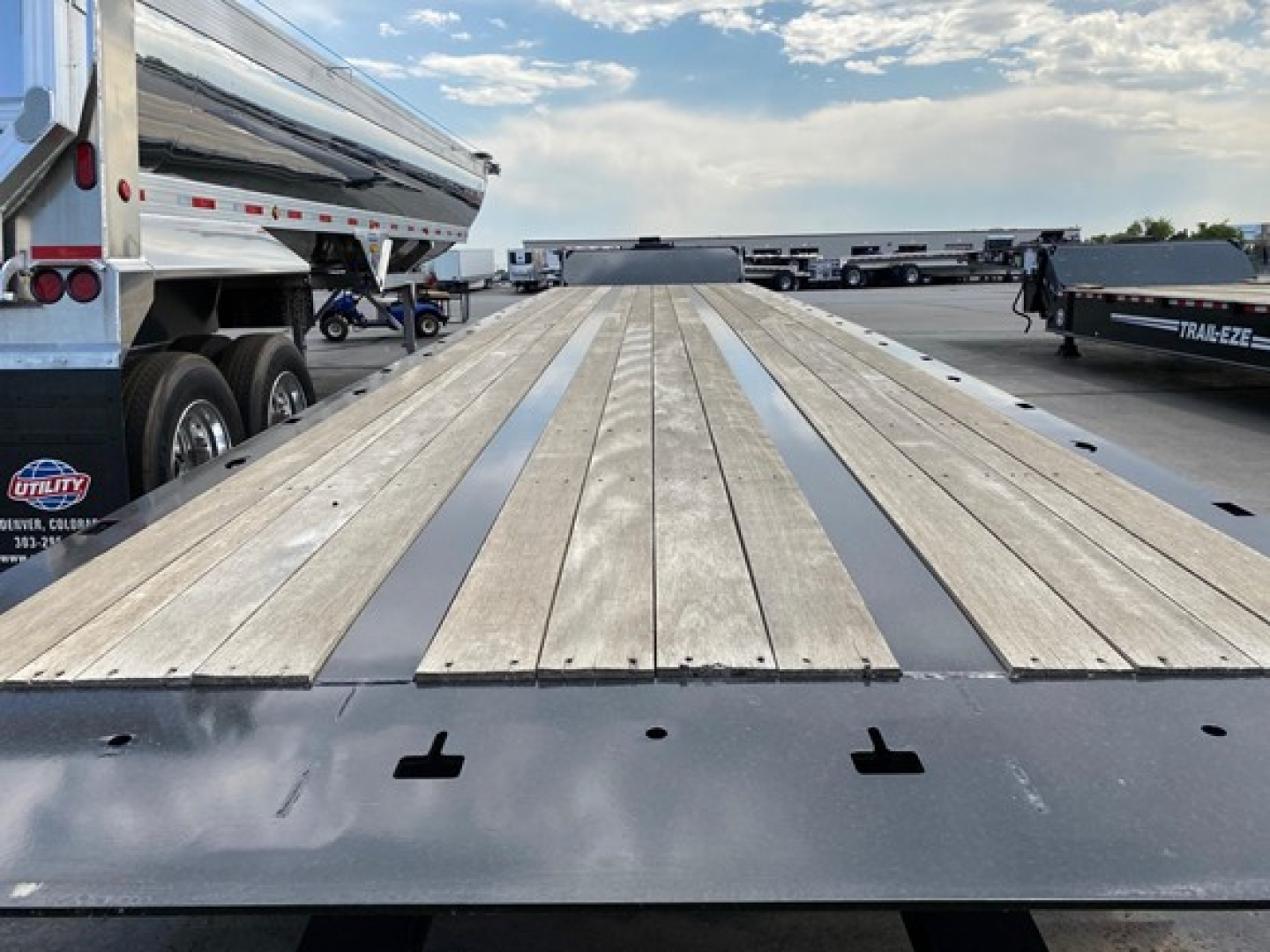 Trail-Eze TE1101 trailer flatbed deck showing wood planks and steel rub rail on the trailer bed.