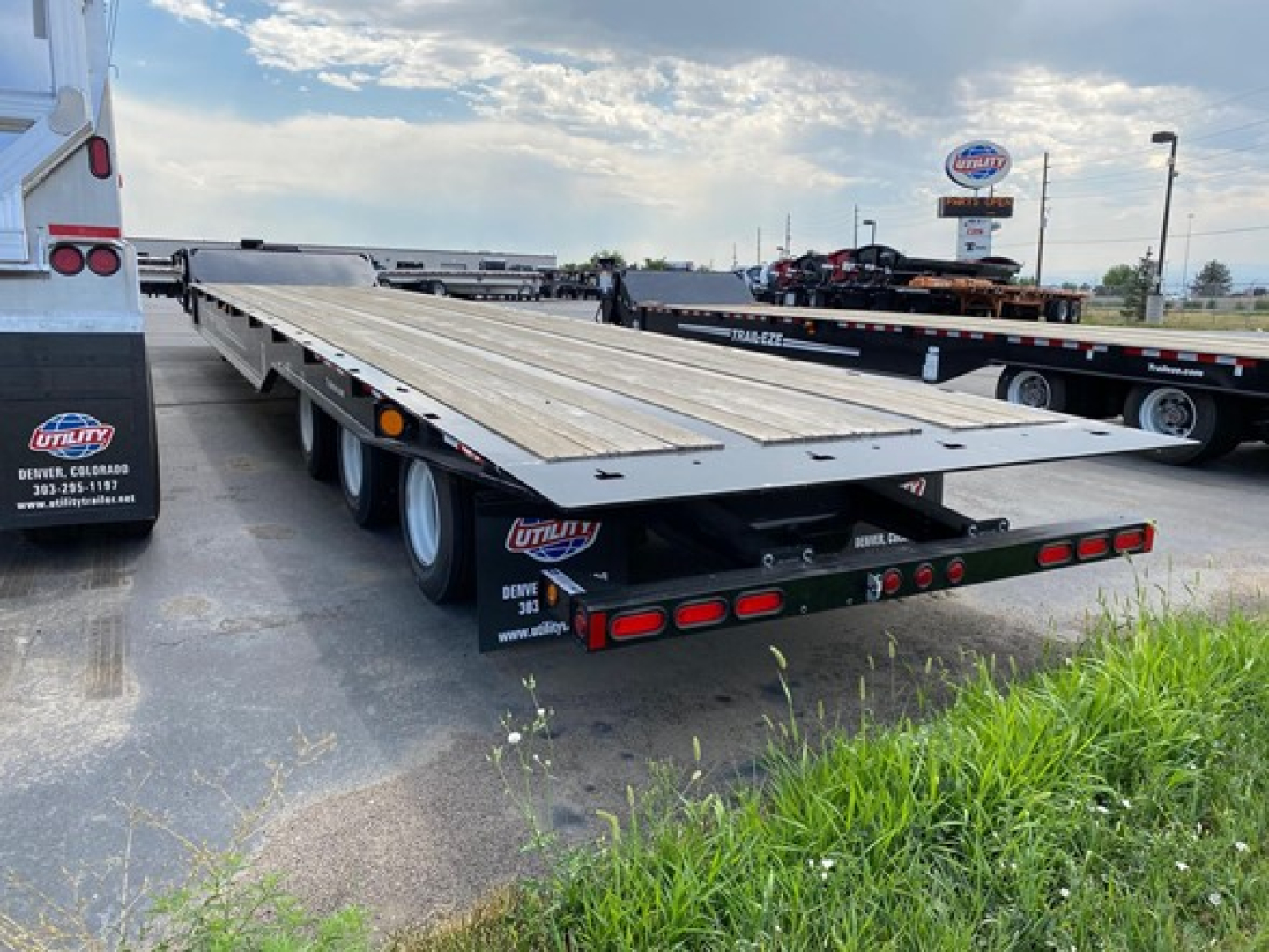 Trailer flatbed with TE1101 model showing long wooden deck and triple-axle configuration in a dealership lot.