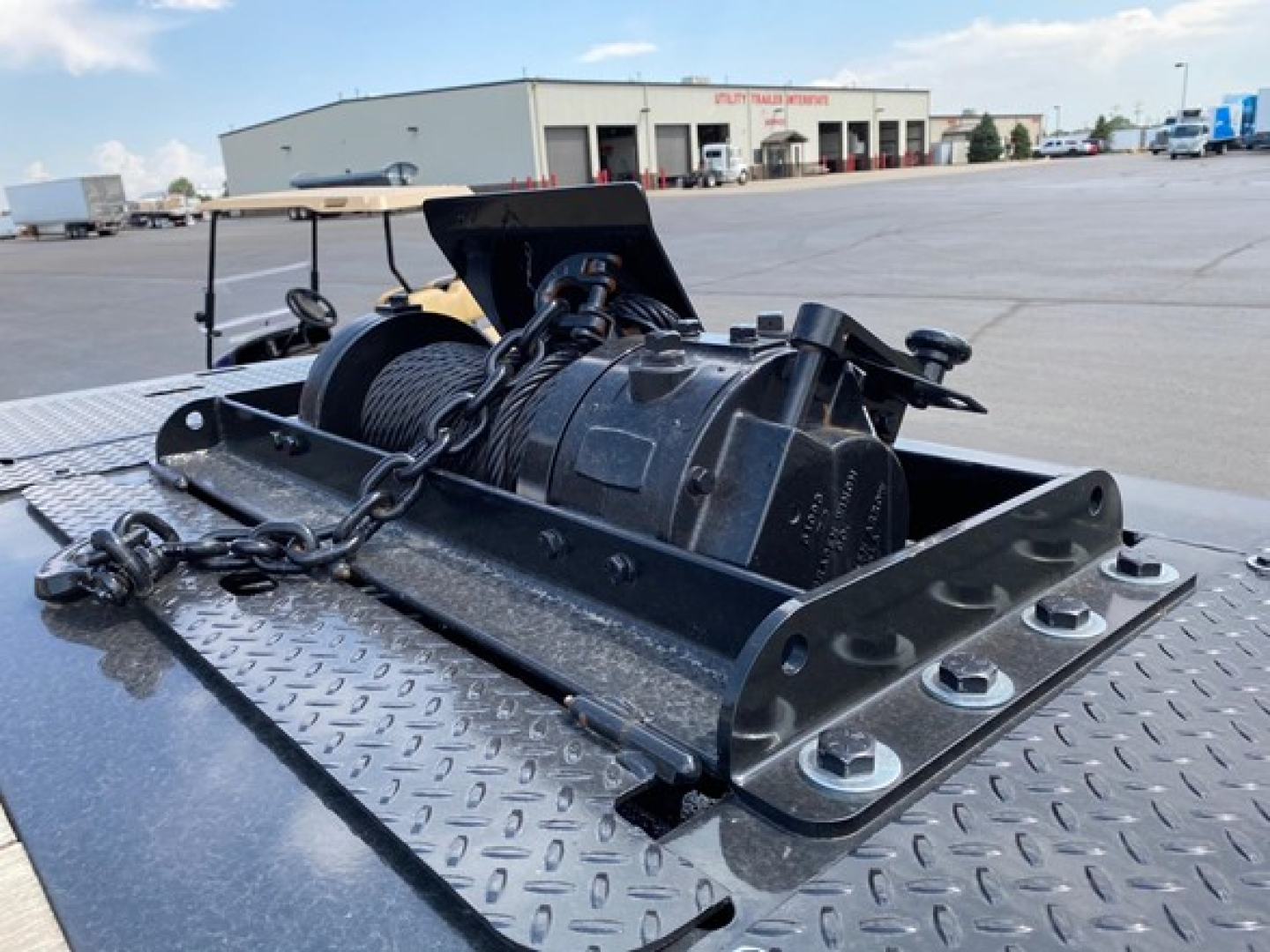 TE1101 trailer winch and mounting hardware on diamond plate deck showing winch drum and hook assembly.