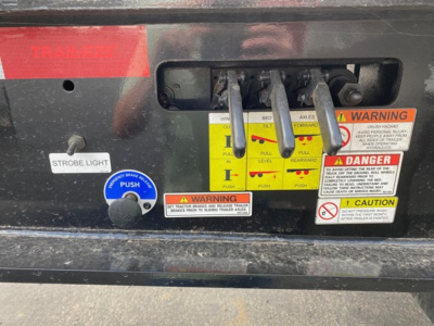 Trailer hitch area showing three control levers labeled WINCH LO, AILER... with warning labels, strobe light switch, and blue PUSH button.