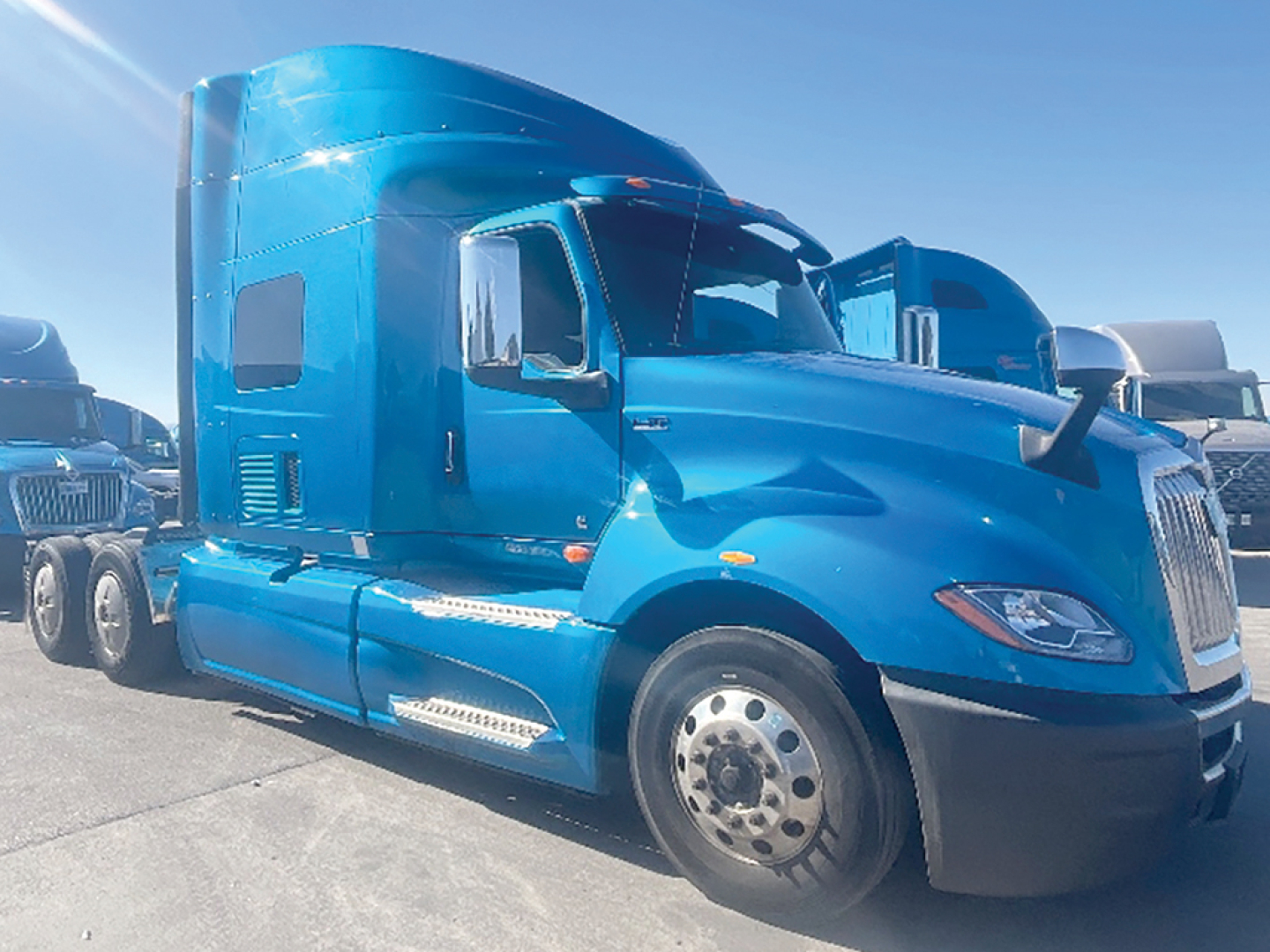 International LT625 truck in blue, side view showing sleeper cab, front wheel, chrome steps, and aerodynamic design.