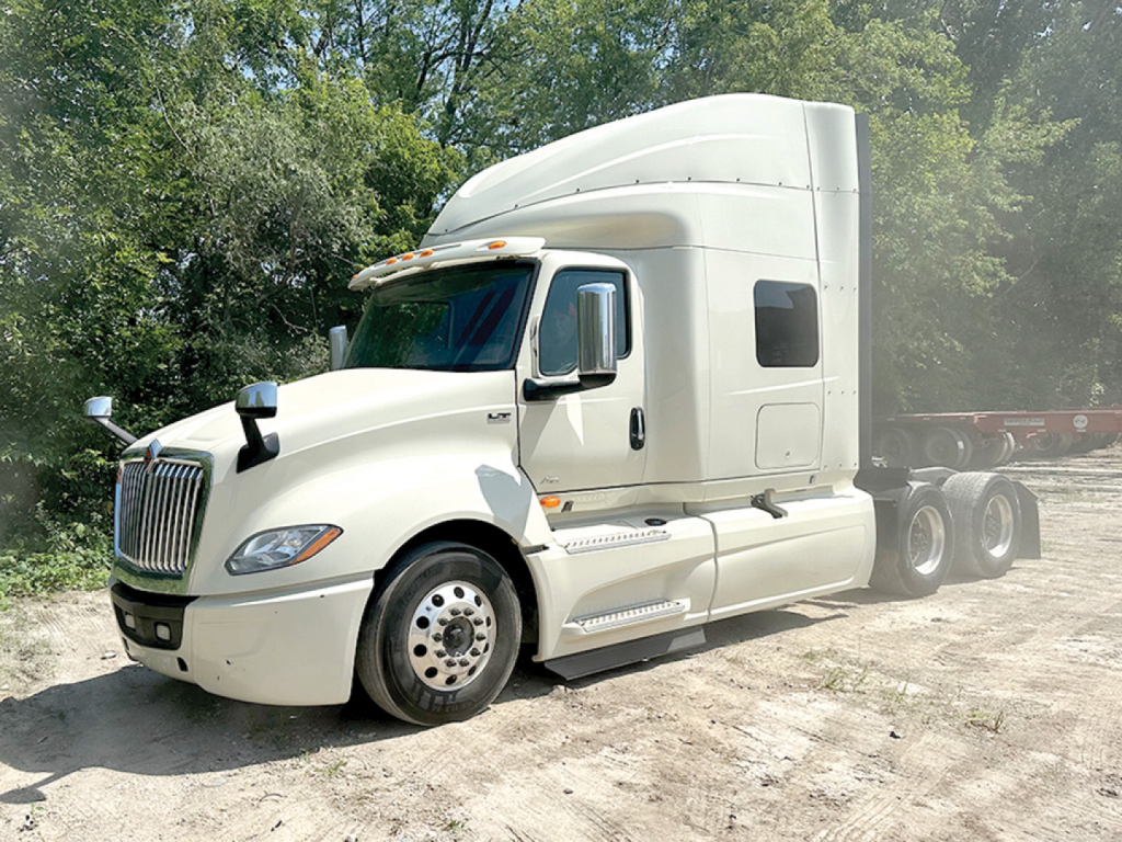Truck side view showing International LT625 tractor with sleeper cab, white paint, large fuel tanks, dual rear axles, and a hood with grille.