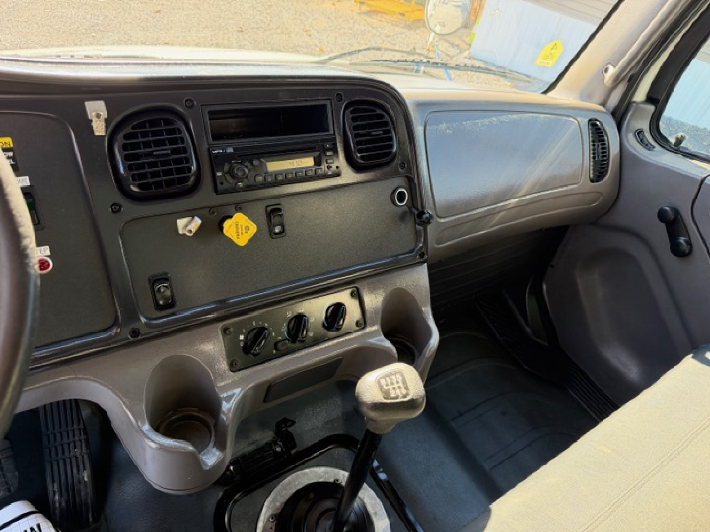 Freightliner M2 106 dashboard and manual transmission shifter with climate controls and radio panel visible