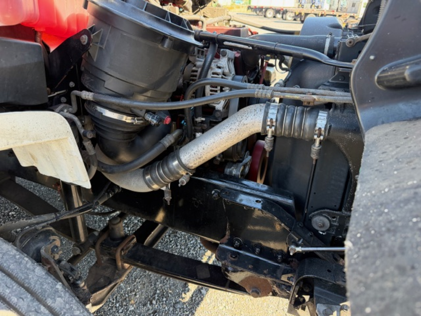 Freightliner M2 106 engine bay showing air intake, hoses, and radiator components; visible engine/drive area with hoses and metal brackets.