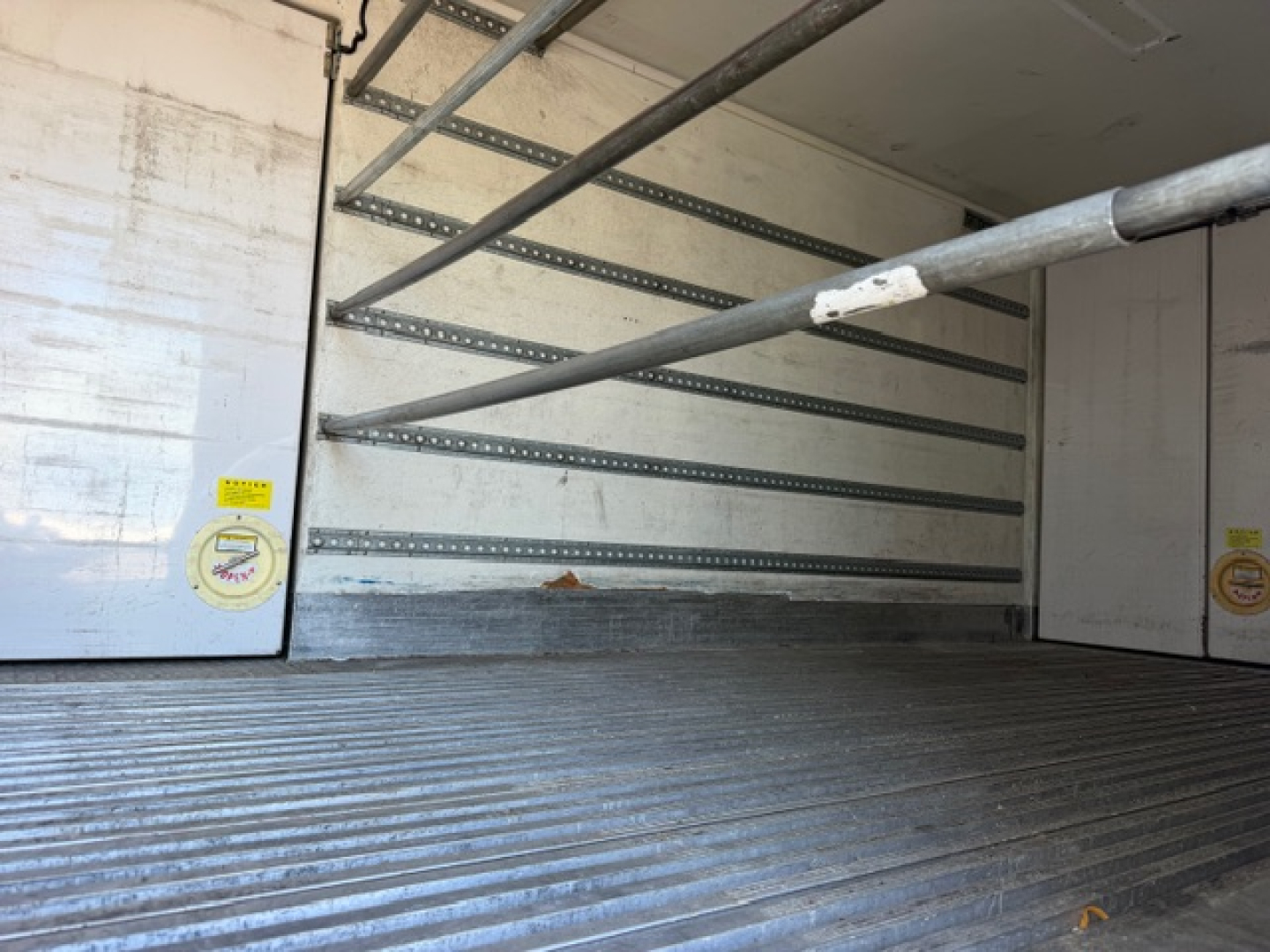 Freightliner M2 106 refrigerated truck cargo area interior with ribbed floor and side wall support rails.