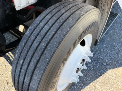 Freightliner M2 106 wheel/tire close-up showing tread and white steel wheel; part of refrigerated truck with visible lug nuts.