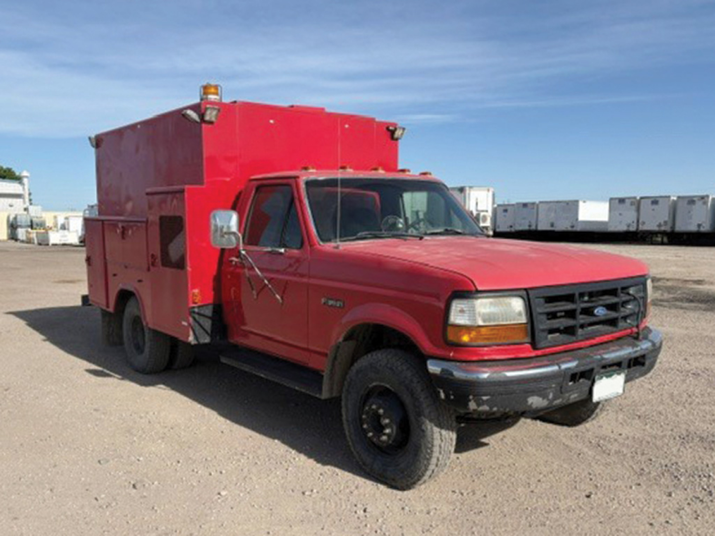 Ford F-350 Super Duty service truck with large red utility box on bed, single cab, front grille, headlights, and amber warning lights on top.