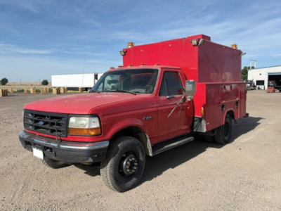 Ford F-350 Super Duty utility/service truck with red utility box on bed, front grille, headlights, and large side mirror.