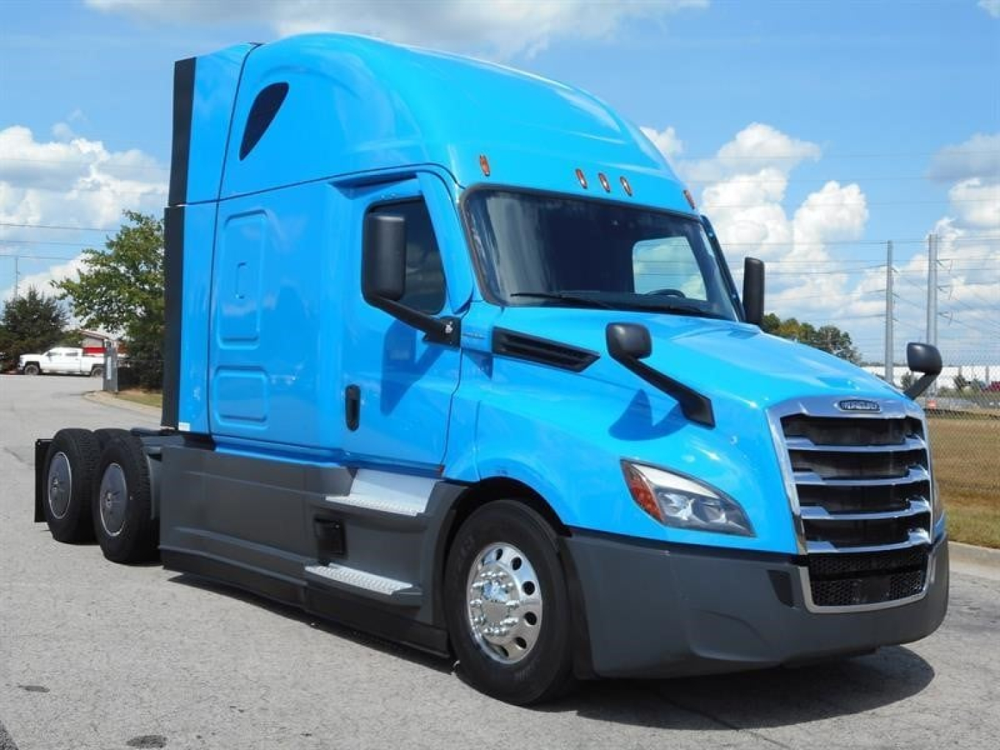 Freightliner Cascadia 126 blue semi-truck front three-quarter view showing sleeper cab, chrome wheels, and black grille.