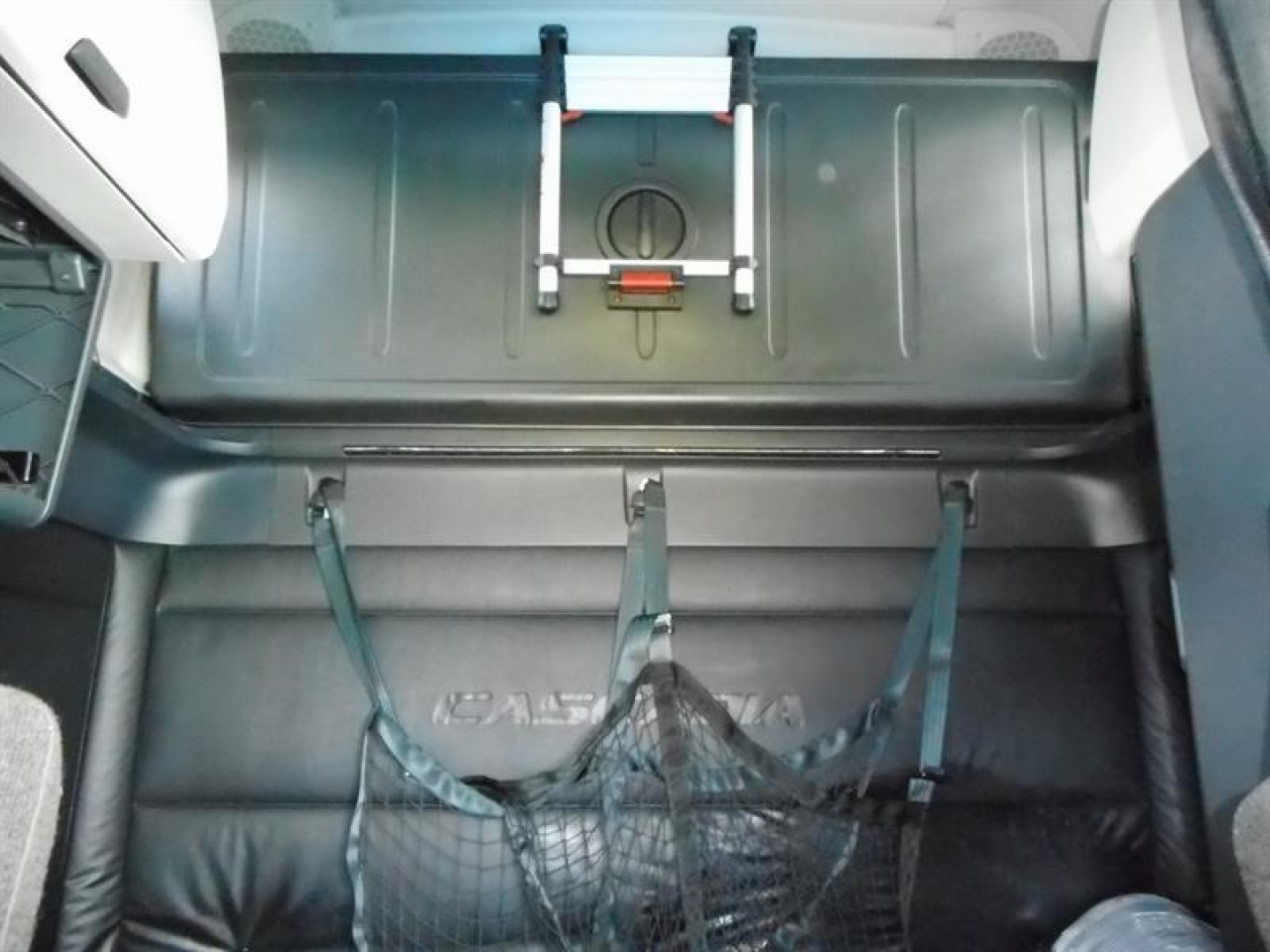 Freightliner Cascadia 126 cab interior showing cargo area with strap-secured nets and overhead storage hatch.