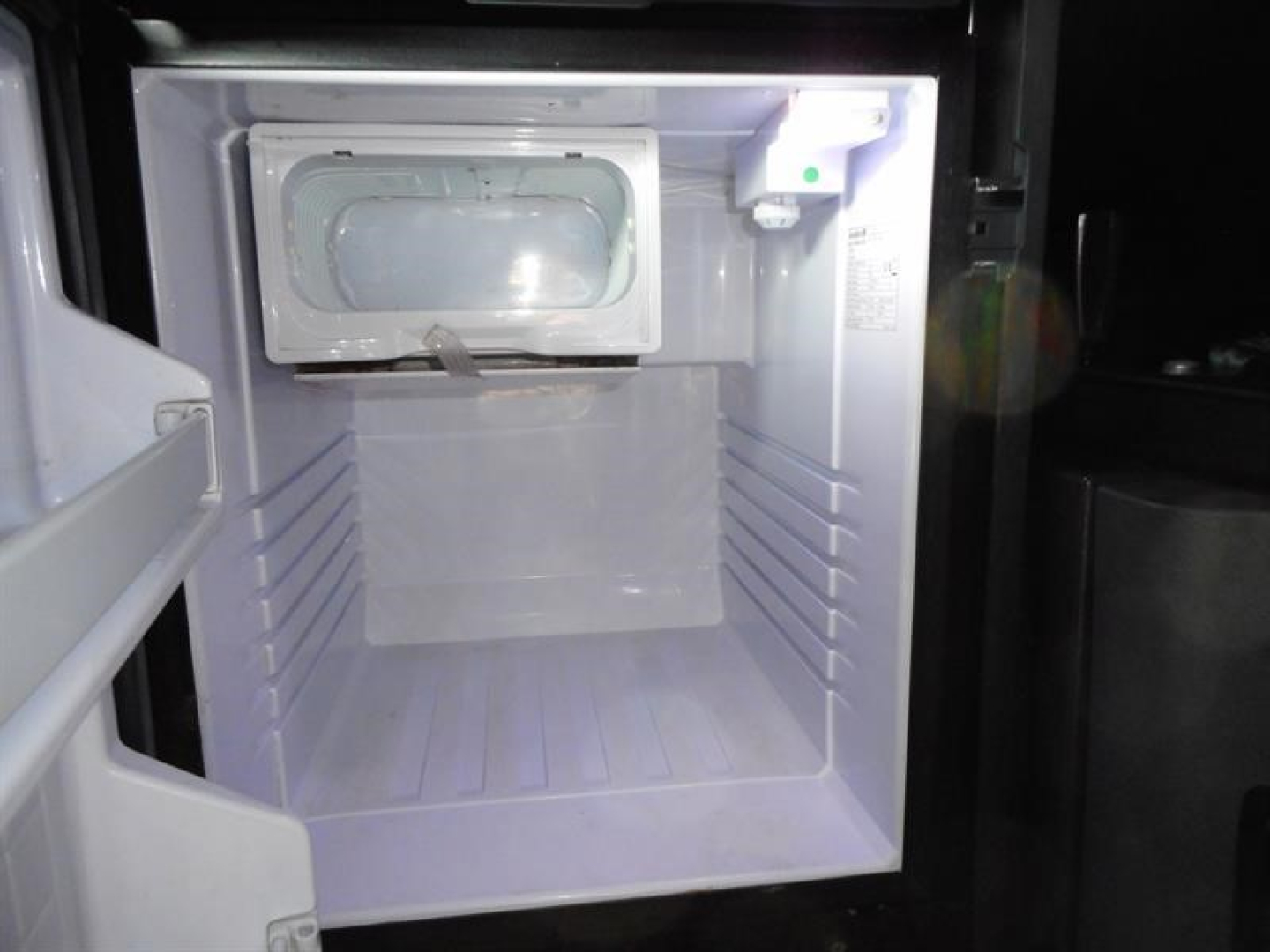 Freightliner Cascadia 126 engine bay showing a small refrigerated compartment with door hatch and white interior.