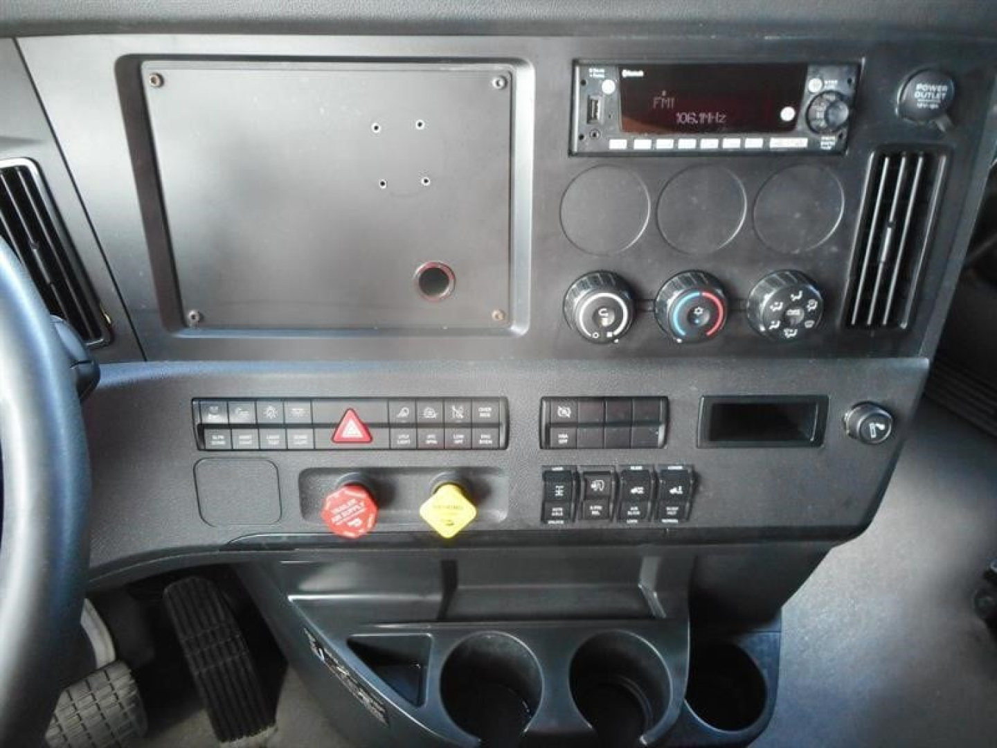 Dashboard of a Freightliner Cascadia 126 with control panels, gauges, and cup holders.