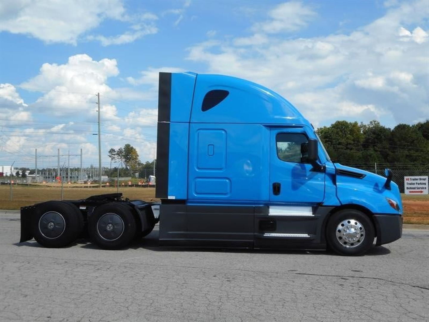 Freightliner Cascadia 126 sleeper cab tractor, side view, blue exterior, 6x4 rear wheels, highway road in background.