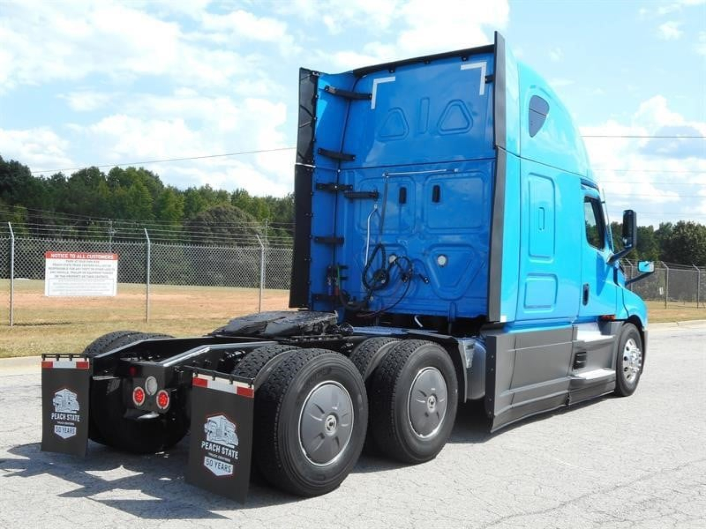Truck rear three-quarter view of a blue Freightliner Cascadia 126 sleeper cab tractor with dual rear axles, showing chassis and fifth wheel, no visible damage.