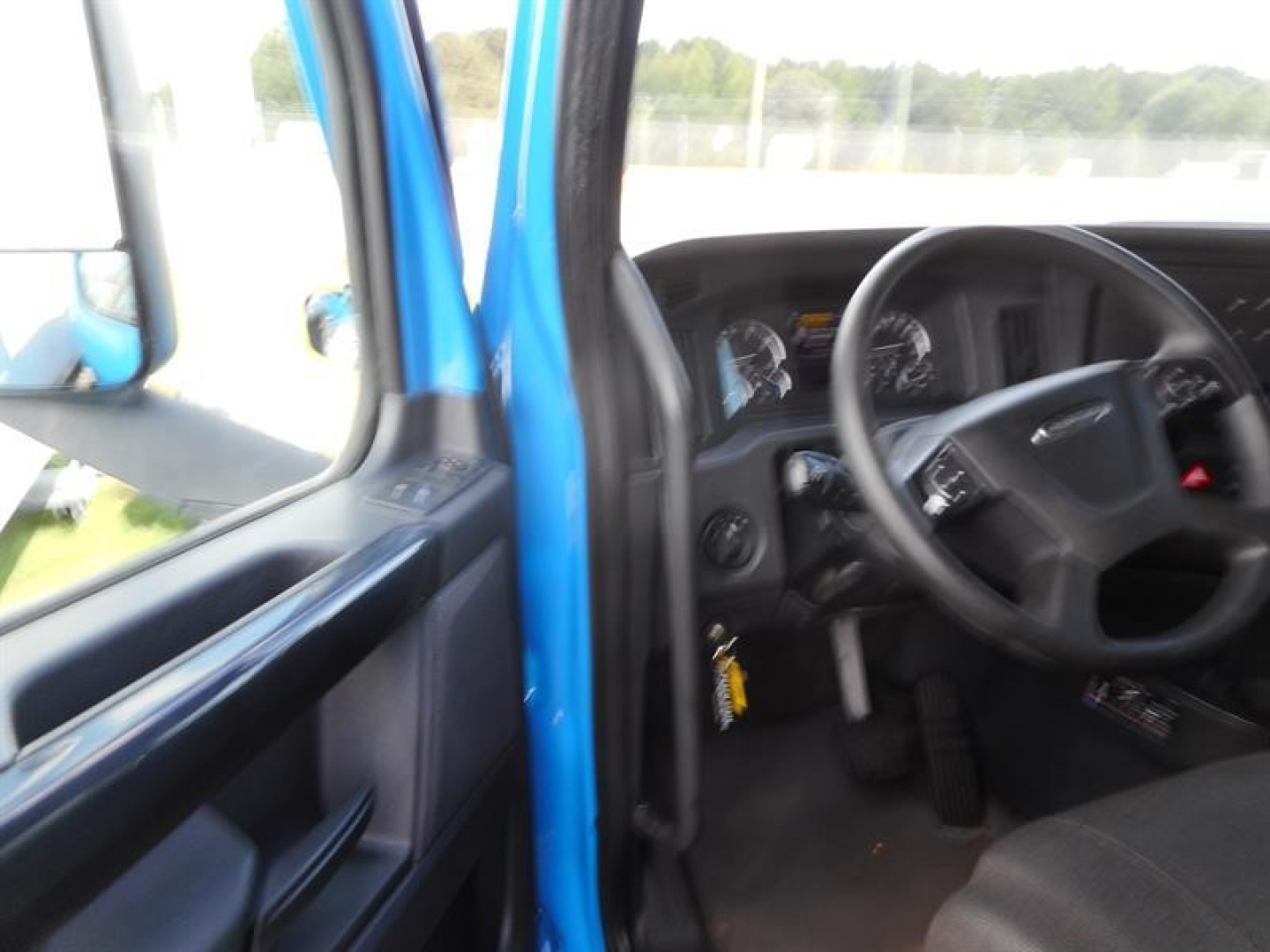 Freightliner Cascadia truck interior view showing steering wheel and instrument cluster from the driver’s door area.