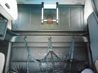 Freightliner Cascadia 126 cab interior showing cargo area with strap-secured nets and overhead storage hatch.
