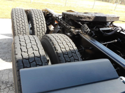 Freightliner Cascadia 126 chassis showing tandem rear axles and tire tread, with undercarriage components visible.