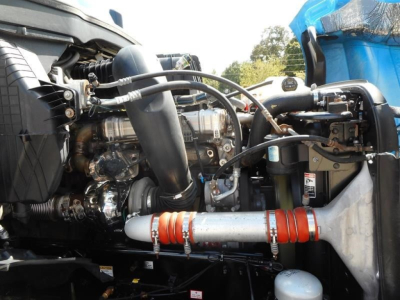 Vehicle engine bay of a Freightliner Cascadia showing turbocharger, intercooler piping, hoses, and hydraulic lines.