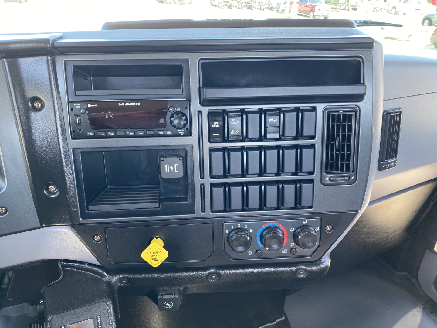 Dashboard of a 2024 Mack MD6 E truck showing radio, control buttons, gauges, and climate controls.