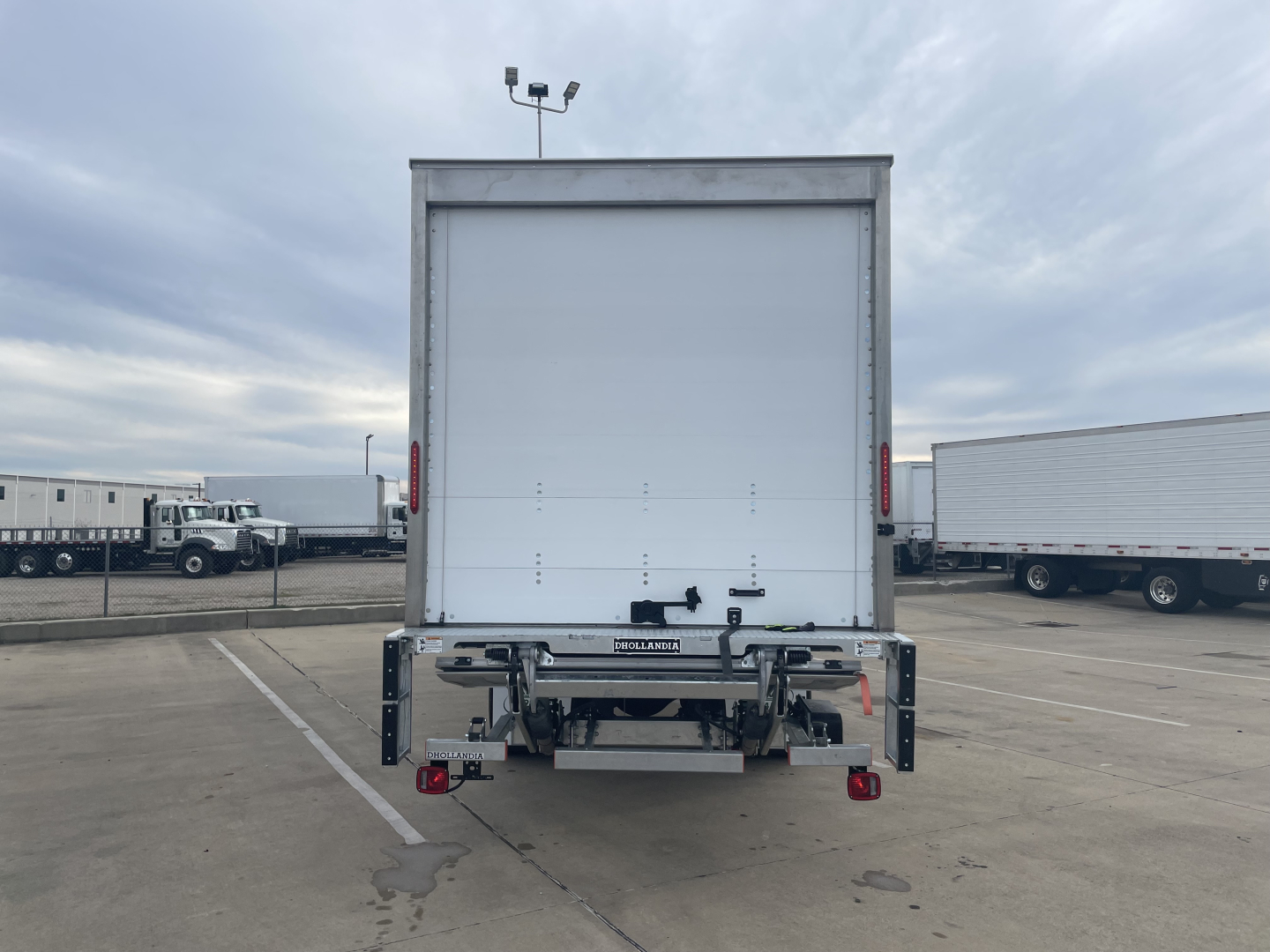 Rear view of a 2024 Mack MD6 E box truck showing cargo area doors and bumper with safety lights.