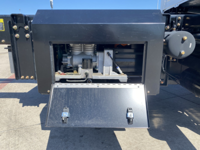 Mack MD6 E engine bay or equipment area showing exposed mechanical components and a metal drop-down access panel.