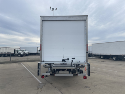 Rear view of a 2024 Mack MD6 E box truck showing cargo area doors and bumper with safety lights.