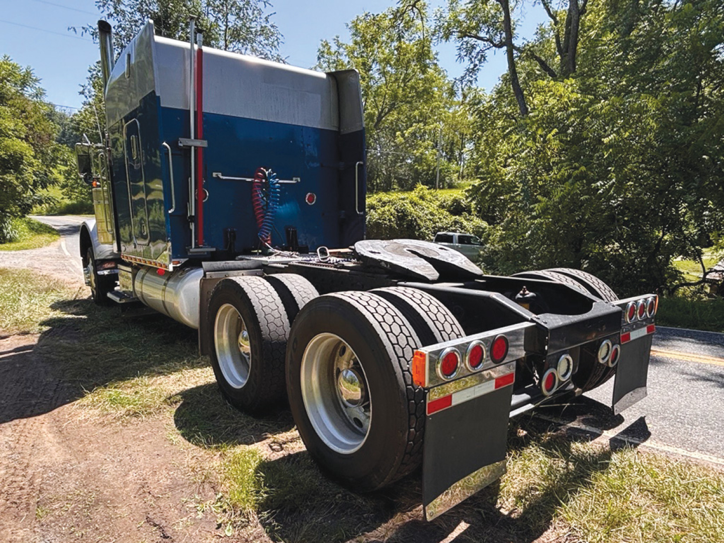 Peterbilt 379 UltraCab extended hood tractor rear view showing dual rear axles and mud flaps.