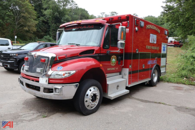 Ambulance mounted on International MH025 chassis showing Hingham Fire Department markings and emergency equipment panel.