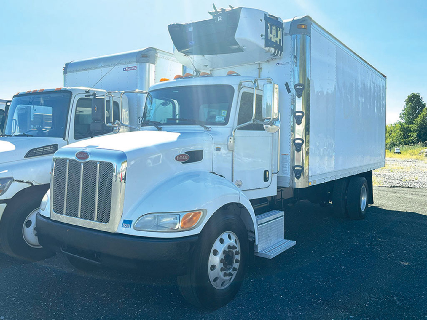 Truck cab and refrigerated box of a 2017 Peterbilt 337 in-service with front grille, white exterior, and cargo box with refrigeration unit on top.