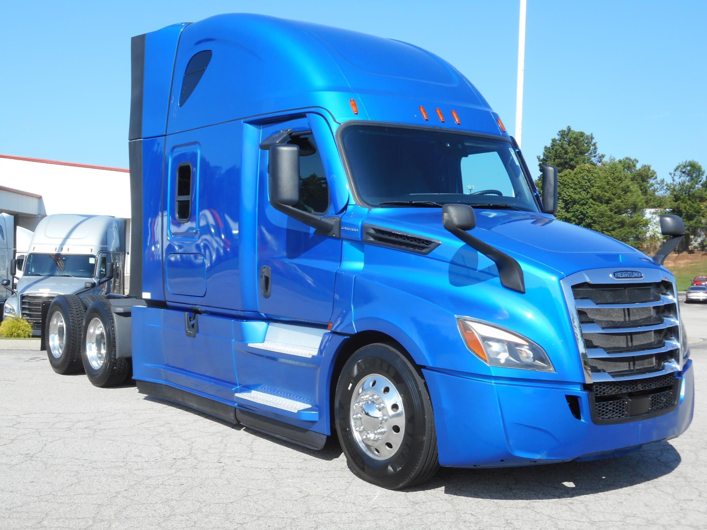Truck image: blue 2022 Freightliner Cascadia 126 conventional sleeper, side view showing cab with aerodynamic mirrors and chrome wheels.