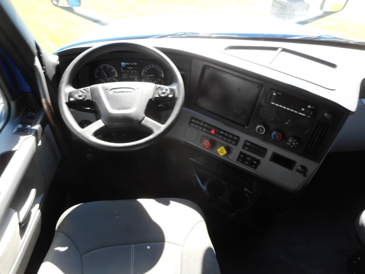 Freightliner Cascadia 126 truck cab interior showing steering wheel, dashboard, and center console. Visible controls and gauges but no legible text.