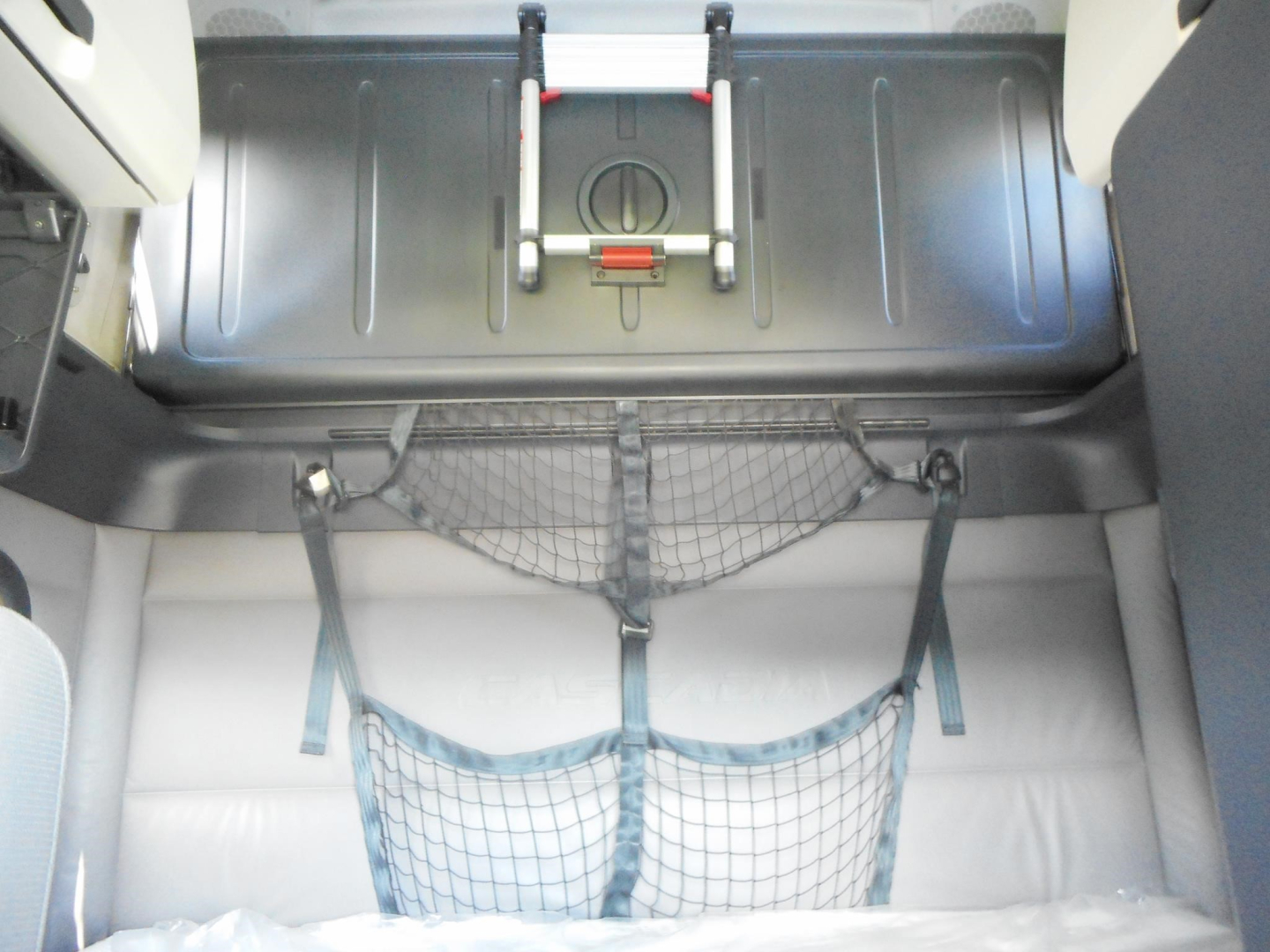 Truck interior showing storage area with netted cargo straps and metal floor, part of a 2022 Freightliner Cascadia 126 sleeper cab.