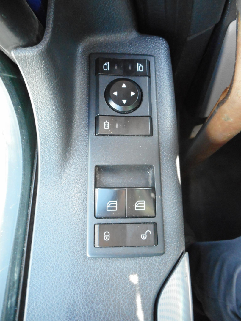 Control panel on driver door of Freightliner Cascadia showing mirror adjustment pad and window/lock switches.