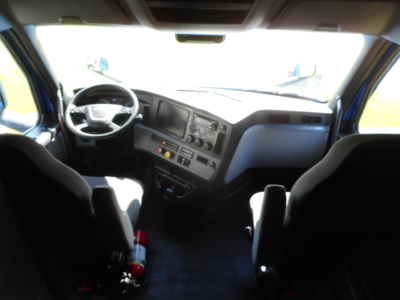 Interior of a Freightliner Cascadia truck cab showing the steering wheel, dashboard, and two front seats.