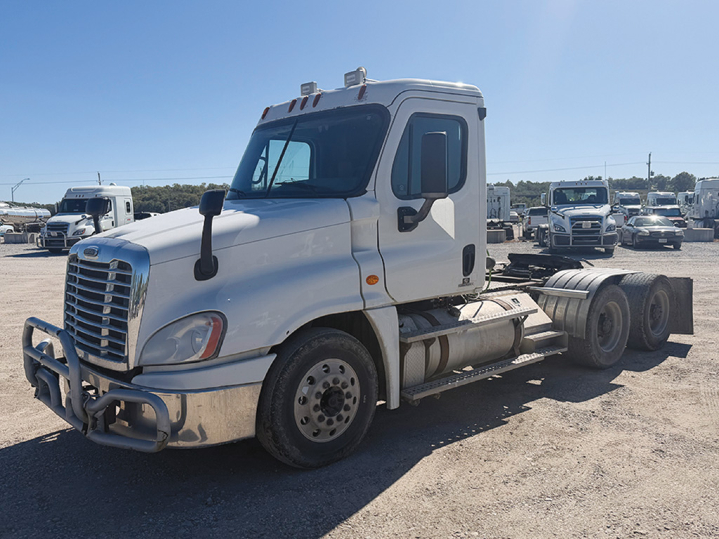 2012 Freightliner Cascadia125 daycab truck side view showing front grille, bumper guards, dual rear wheels, and white cab.