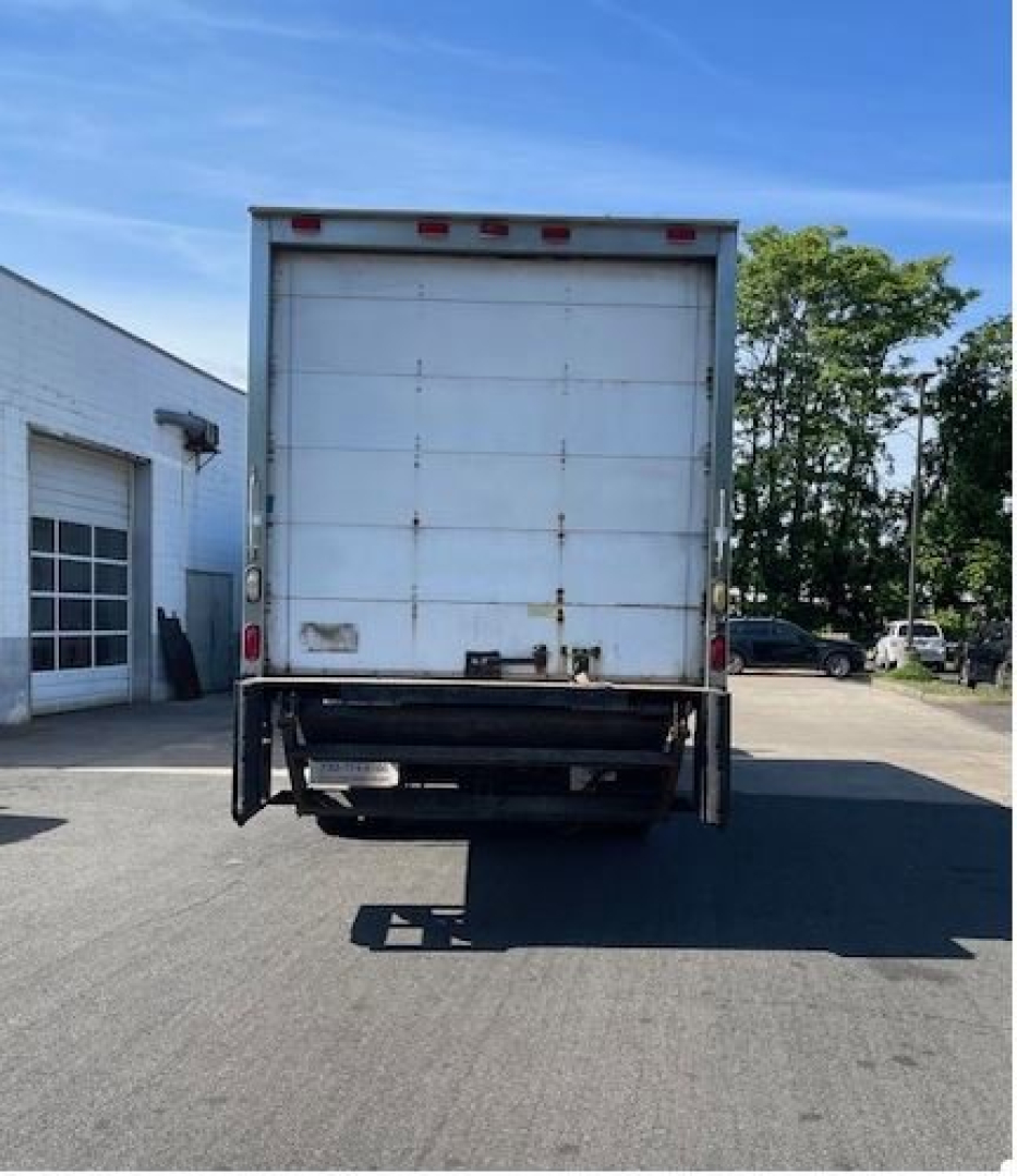 Rear view of a box truck showing closed cargo door and bumper; no visible text readable on the truck itself.