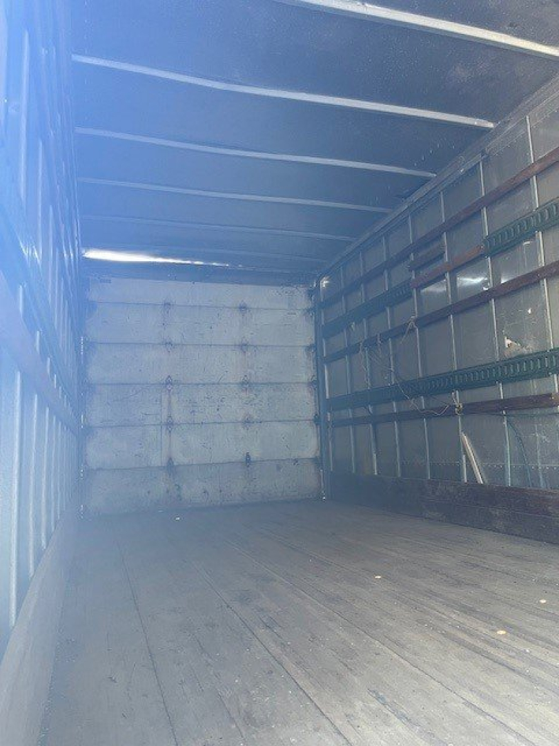 Truck interior showing empty cargo box with wooden floor and side panels.