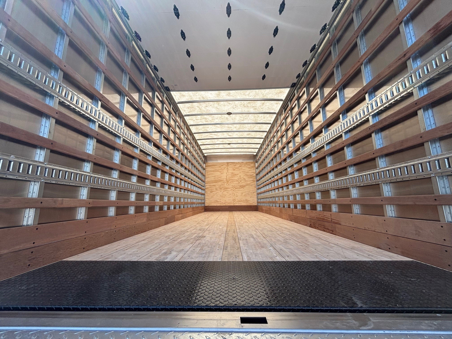 Mack MD6 box truck interior trailer cargo area with wooden side walls and metal ribbing, empty load space.