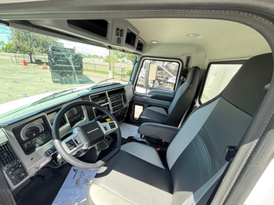 Cab interior of a 2026 Mack MD6 truck showing steering wheel, dashboard, driver seat, and front passenger seat with light gray and black upholstery.