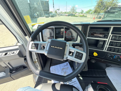 Close-up of Mack MD6 dash and steering wheel with gauges, center console, and control buttons visible.