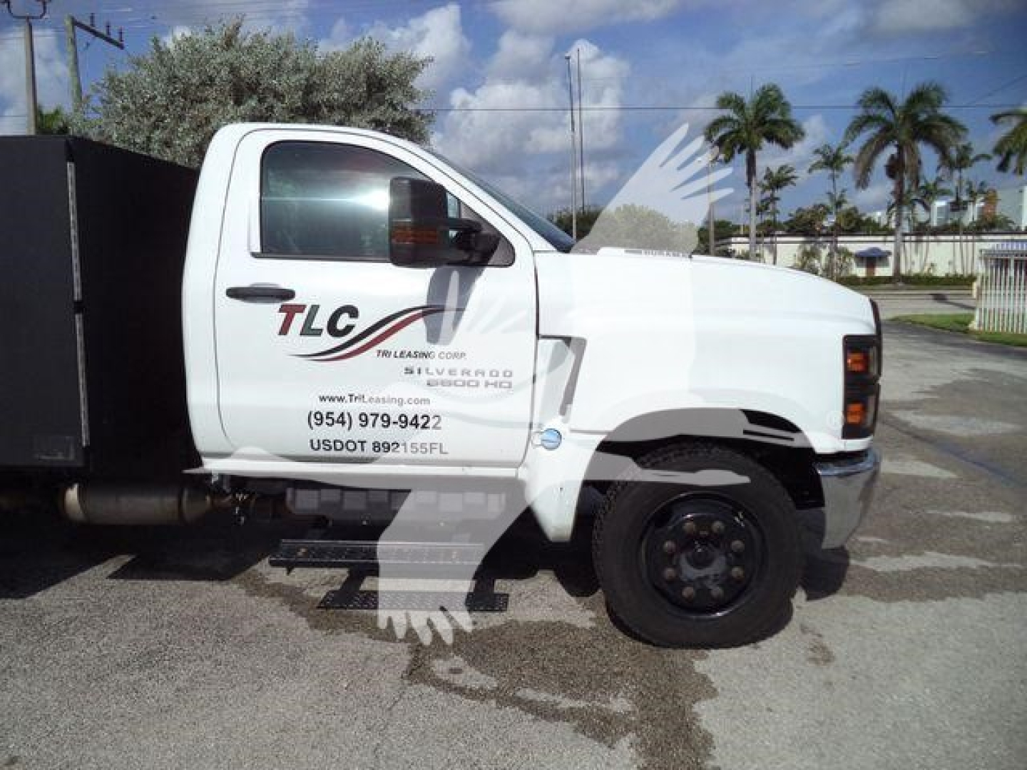 Chevrolet Silverado 6500HD utility truck side view showing TLC lettering on white cab with black wheel, stock number J05524.