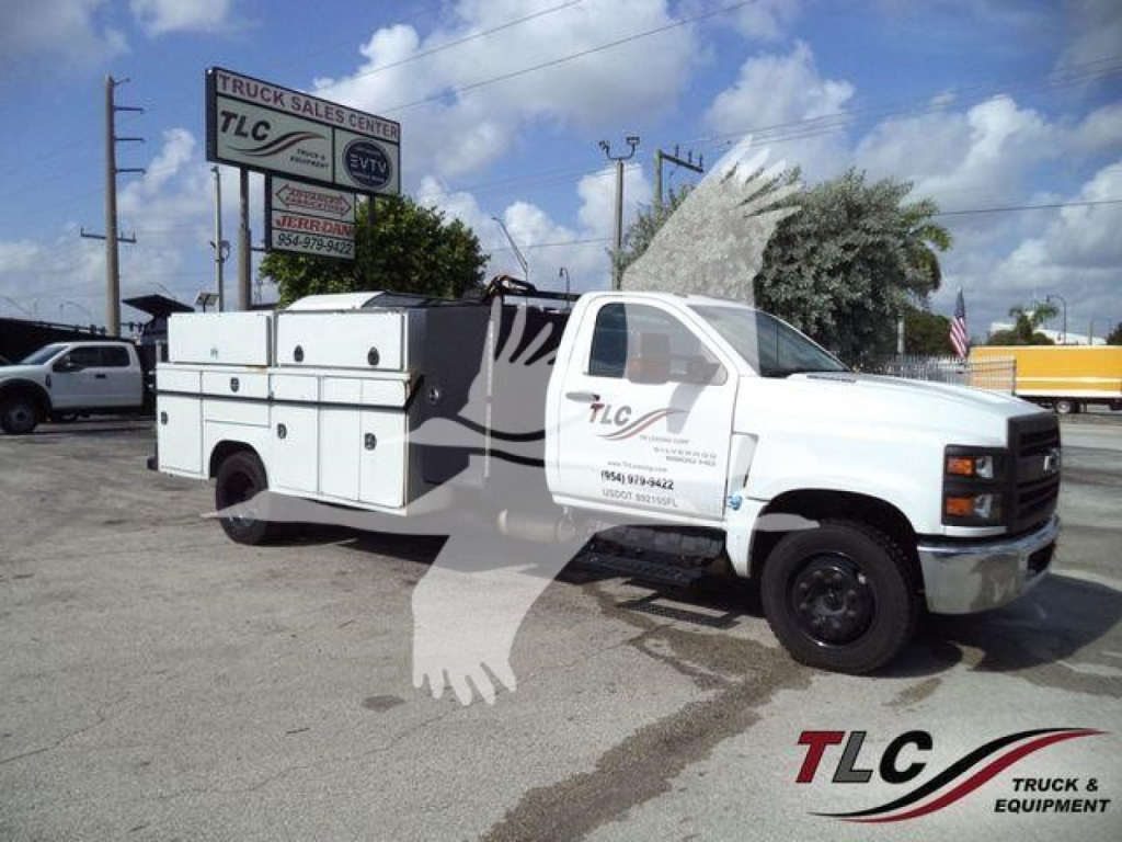 Service/Utility truck bay area with multiple equipment compartments and TLC Truck Sales Center sign in background.