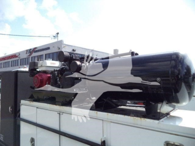 Truck-mounted generator on bed of a utility truck in service use showing gasoline engine and exhaust components.