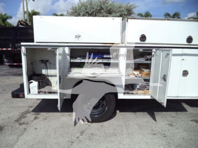 Service body compartments open on a 2023 Chevrolet Silverado 6500HD work truck showing storage boxes and tools.