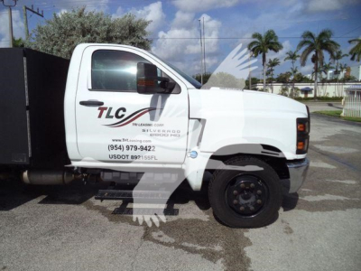 Chevrolet Silverado 6500HD utility truck side view showing TLC lettering on white cab with black wheel, stock number J05524.