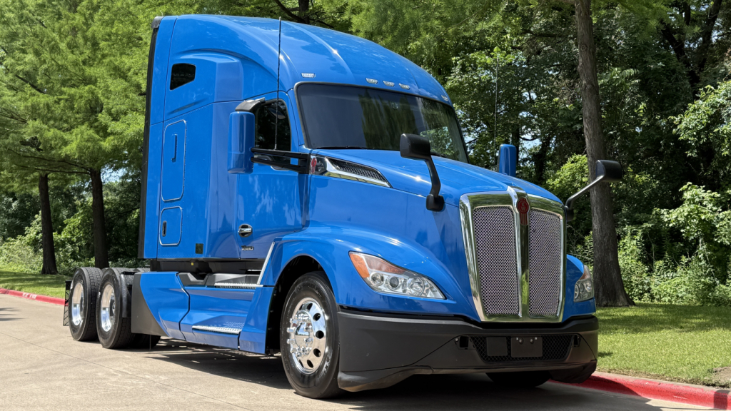 Kenworth T680 truck cab and front end in blue, side view showing aerodynamic mirrors and grille.