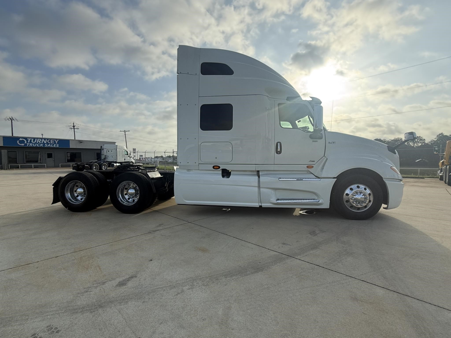 Truck side view of a white 2020 International LT conventional sleeper tractor showing cab with window, fuel tanks, and dual rear axles.