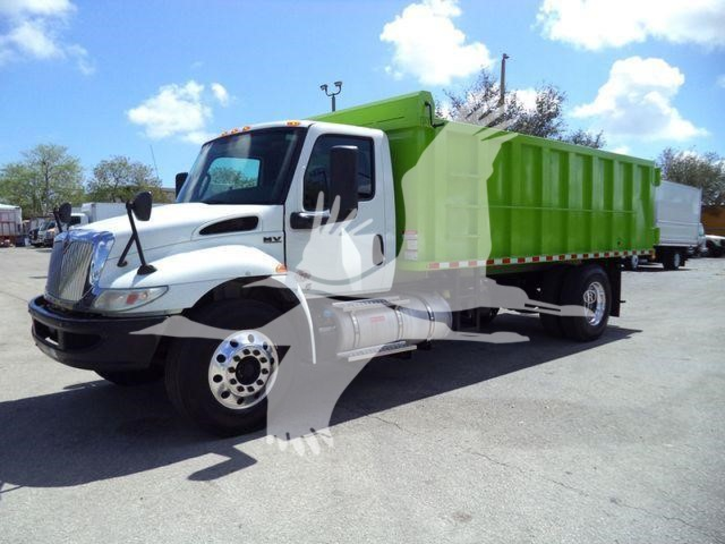 Dump truck with white cab and bright green dump body in a lot, front angle view showing wheel and side profile.