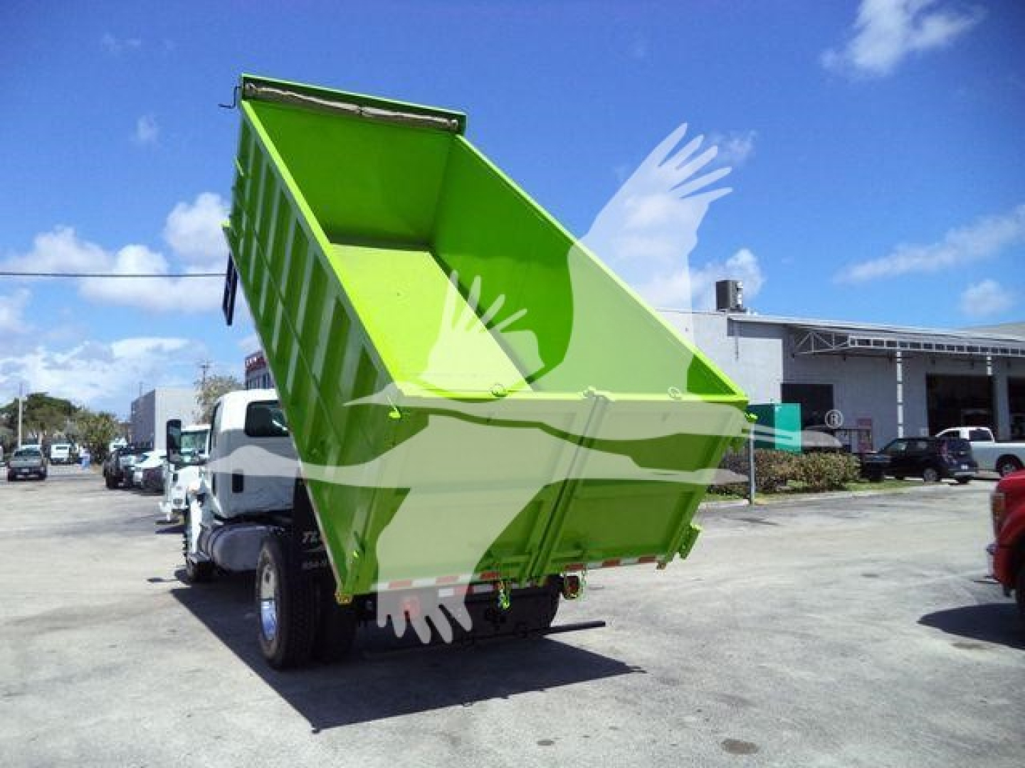 Dump truck rear view with lime-green dump bed raised, chassis and wheels visible in a dealership lot.