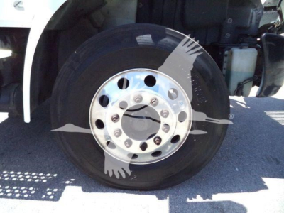 Truck wheel/driver side front wheel showing chrome hub with lug nuts and tire; fender and part of cab visible.
